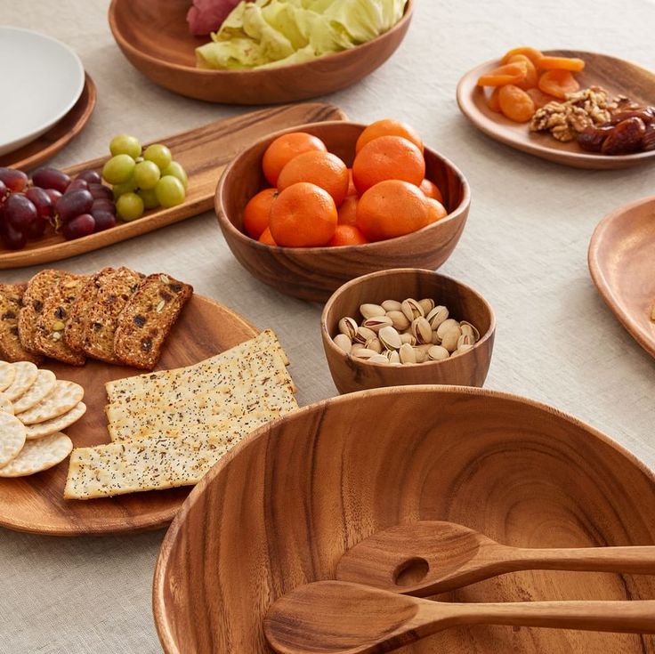 Assorted snacks including fruits, nuts, and crackers on wooden plates.
